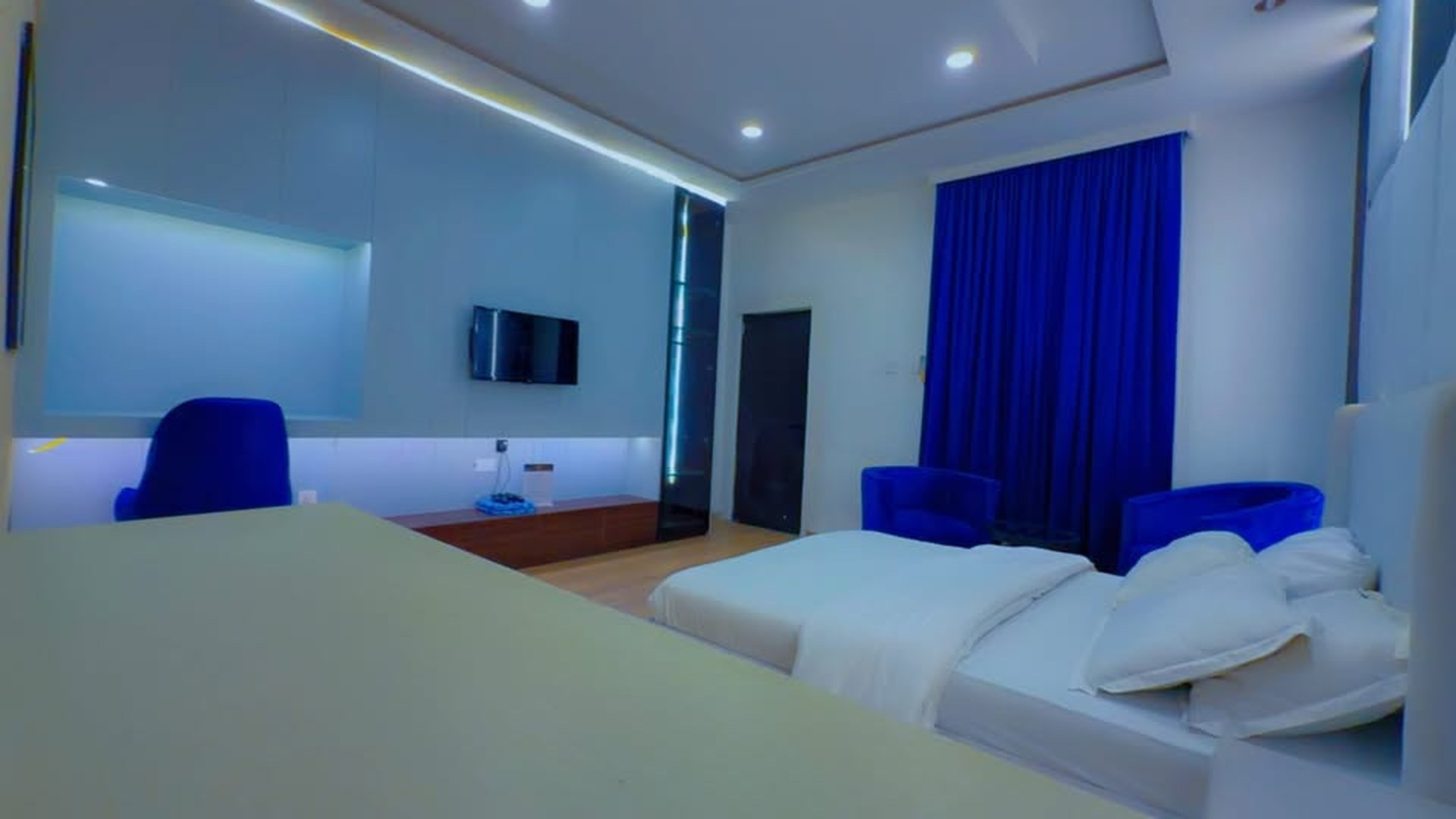 Studio Deluxe bedroom with white bed and cobalt rug